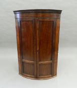 A Georgian mahogany bow front corner cupboard. 118 cm high.