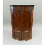 A Georgian mahogany bow front corner cupboard. 118 cm high.