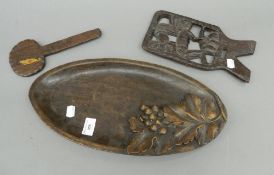 An antique wooden oval shaped tray with carved vine decoration and a small antique carved African