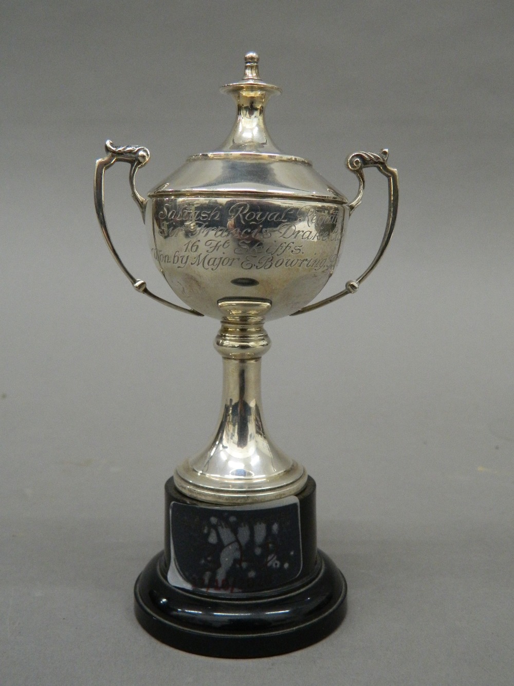 A small silver lidded trophy cup, on stand. 13.5 cm high overall. 57 grammes of weighable silver.