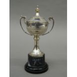 A small silver lidded trophy cup, on stand. 13.5 cm high overall. 57 grammes of weighable silver.