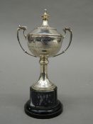 A small silver lidded trophy cup, on stand. 13.5 cm high overall. 57 grammes of weighable silver.
