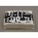 A silver snuff box, the lid inset with a cricket team. 5 cm wide.