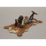 A cold painted bronze model of a boy on a tiger rug. 12 cm long.