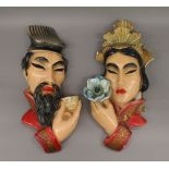 A pair of plaster wall masks depicting a Chinese man and woman.