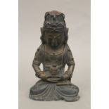 A seated bronze deity holding a teapot. 18 cm high.