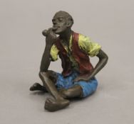 A cold painted bronze model of a boy smoking a pipe. 6 cm high.