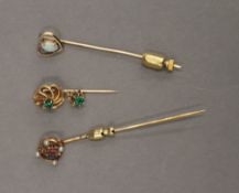 An unmarked gold seed pearl and gem set stickpin, together with two others. The former 6.5 cm high.