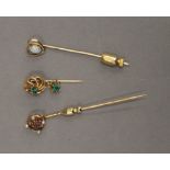 An unmarked gold seed pearl and gem set stickpin, together with two others. The former 6.5 cm high.