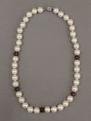 A pearl necklace with diamond set enamel spacers. 45 cm long.