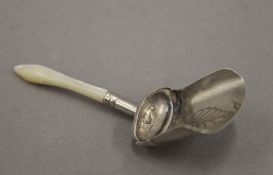 A silver and mother-of-pearl caddy spoon. 7 cm long.