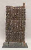 A carved wooden tribal Dogon door, on a display stand. 66.5 cm high.