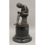 A Grand Tour bronze of a seated man picking a thorn from his foot, on socle base. 32 cm high.