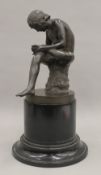 A Grand Tour bronze of a seated man picking a thorn from his foot, on socle base. 32 cm high.