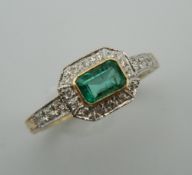 An Art Deco style 9 ct gold, emerald and diamond ring with diamond set shoulders and engraved shank.