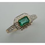 An Art Deco style 9 ct gold, emerald and diamond ring with diamond set shoulders and engraved shank.