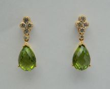 A pair of 18 ct gold peridot and diamond drop earrings. Each 2.5 cm high.