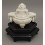 A Chinese carved white jade lidded censer, on a carved hardwood stand. The censer 10 cm high.