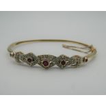 A 9 ct gold ruby and diamond bangle. 6.5 cm wide. 10.1 grammes total weight.