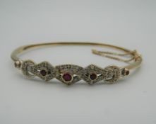 A 9 ct gold ruby and diamond bangle. 6.5 cm wide. 10.1 grammes total weight.