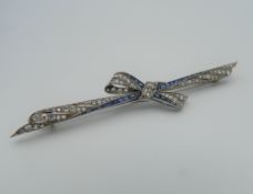 An Edwardian platinum, diamond and sapphire bow brooch with an 18 ct yellow gold hallmarked pin.