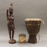 A vintage tribal carved statue of a female warrior and two African drums. The former 54 cm high.