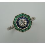 An Art Deco style platinum, emerald, sapphire and diamond ring with diamond set shoulders.