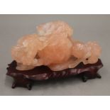 A Chinese carved rose quartz group formed as dogs-of-fo, on a carved wooden stand.