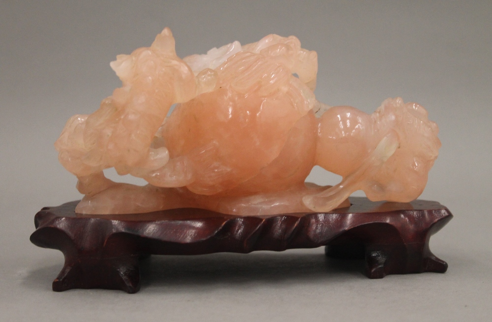 A Chinese carved rose quartz group formed as dogs-of-fo, on a carved wooden stand. - Image 2 of 5