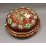 A Victorian squat stool on bun feet, with tapestry covered cushion. 30 cm diameter.