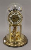 A brass anniversary clock under a glass dome. 28 cm high.