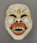 An Indonesian carved and painted street players mask, with the interior inscribed. 18.5 cm high.