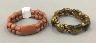 A goldstone bracelet and a tigers eye bracelet.