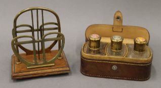 An early 20th century brass mounted letter rack and a leather cased set of perfume bottles.