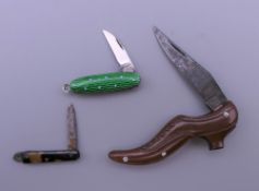 Three miniature pen knives, one in the shape of a shoe. The smallest 2.5 cm long.