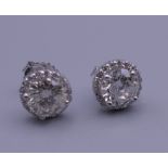 A pair of 18 ct white gold diamond ear studs, each central stone spreading to approximately 1 carat.
