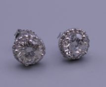 A pair of 18 ct white gold diamond ear studs, each central stone spreading to approximately 1 carat.