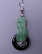 An Art Deco carved apple green jade, onyx and diamond pendant, set in platinum, on a platinum chain.