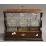 A three bottle tantalus. 41 cm wide.