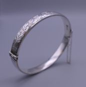 An embossed silver bangle form bracelet. 6.5 cm wide. 12.5 grammes.