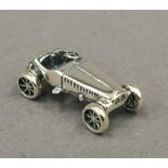 A small silver model of a car. 3 cm long.