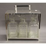 A Three bottle silver plated tantalus. 28 cm wide.