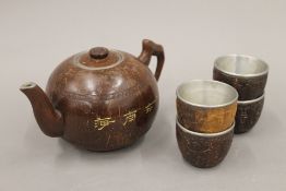 A carved coconut teapot and four cups. The teapot 10 cm high.