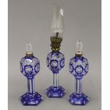 A small blue flashed glass oil lamp and a pair of scent bottles en-suite. The former 27 cm high.