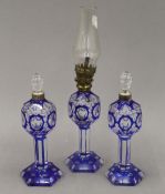 A small blue flashed glass oil lamp and a pair of scent bottles en-suite. The former 27 cm high.