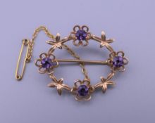 A 9 ct gold and amethyst brooch. 3.25 cm wide. 3.9 grammes total weight.