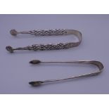 A pair of silver sugar tongs and another pair of sugar tongs. The former 13 cm long. 39.9 grammes.
