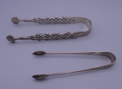 A pair of silver sugar tongs and another pair of sugar tongs. The former 13 cm long. 39.9 grammes.