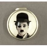 A silver pill box depicting Charlie Chaplin. 2.5 cm diameter.