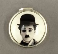 A silver pill box depicting Charlie Chaplin. 2.5 cm diameter.